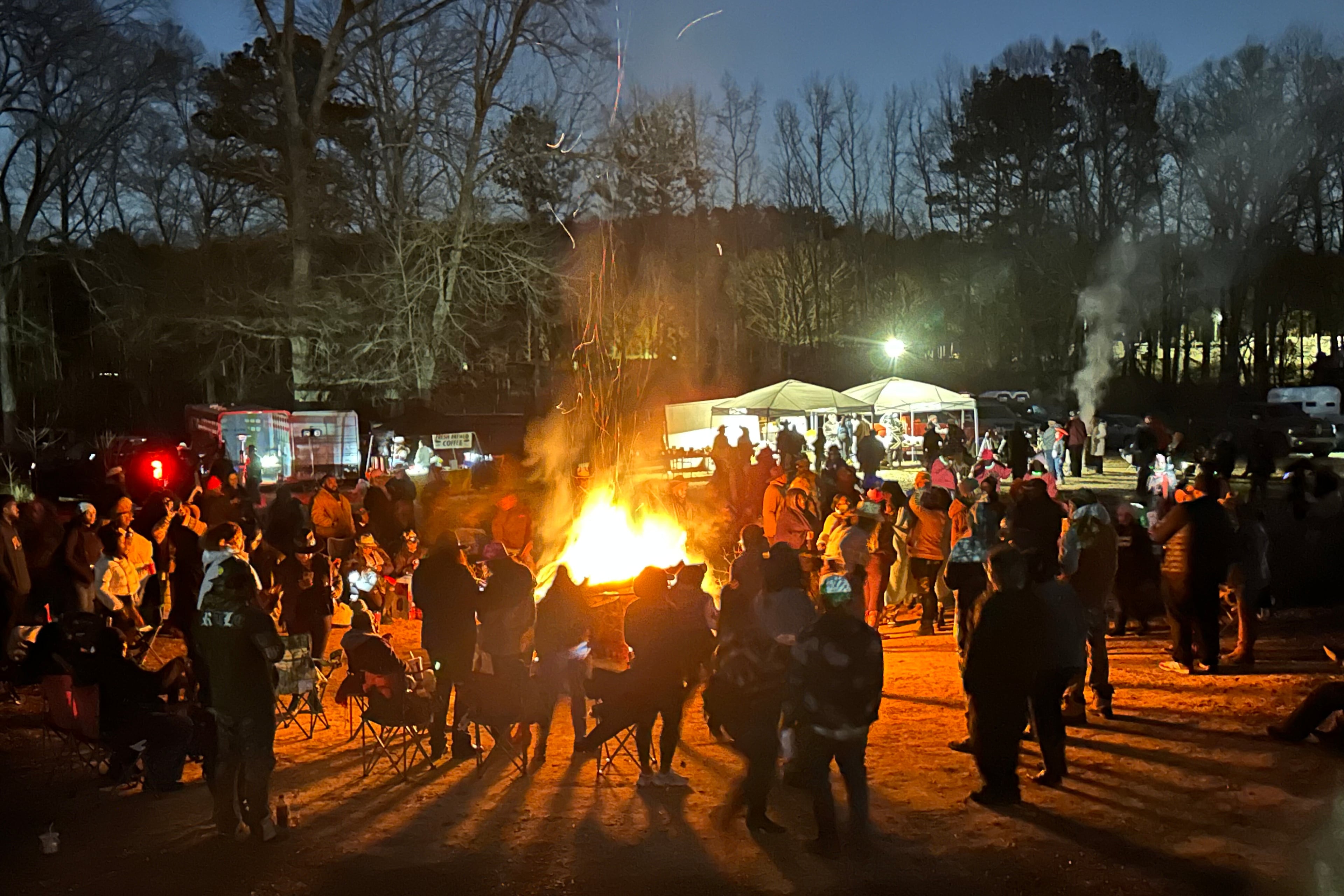 Participants in a trail ride hosted by the group Cowboys & Creatives gather around a bonfire in April 2025.