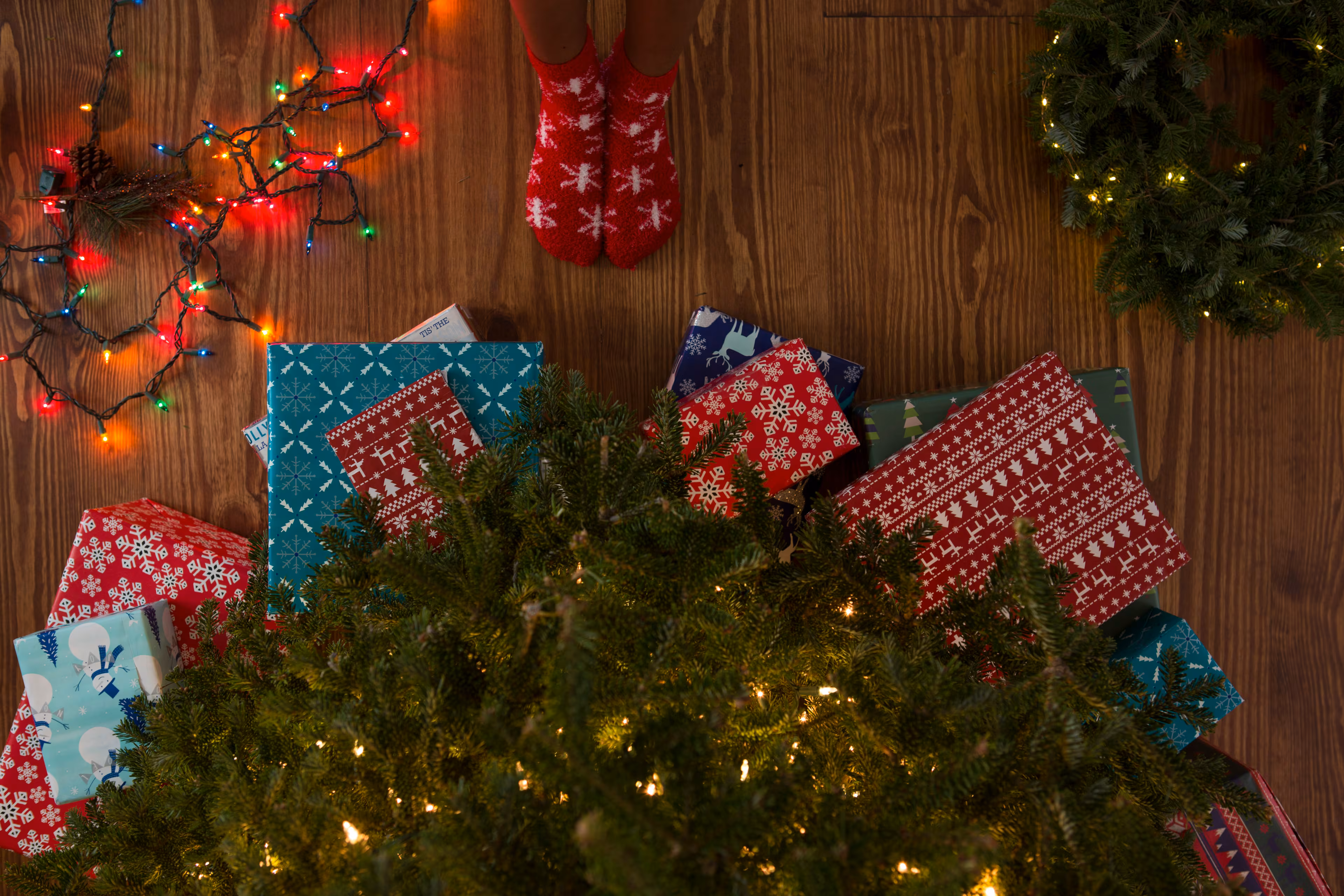 A child stands under a Christmas tree, excited to open presents. But the holiday season is more than the festive glitz and glamour. (Courtesy of Thought Catalog on Unsplash)