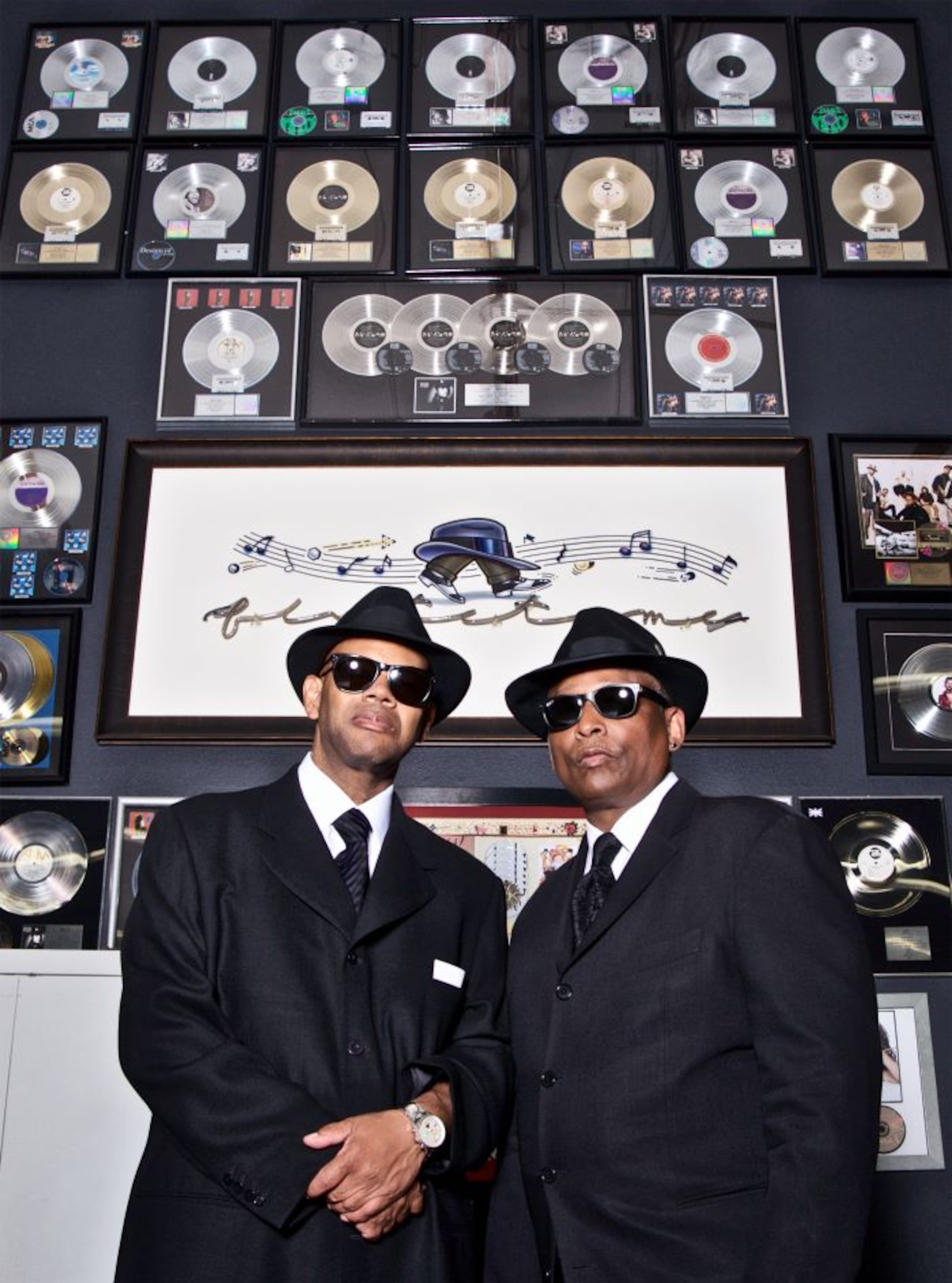 Producers Jimmy Jam and Terry Lewis pose in front of their gold and platinum awards for songwriting and producing. (Courtesy of Flyte Tyme Productions)