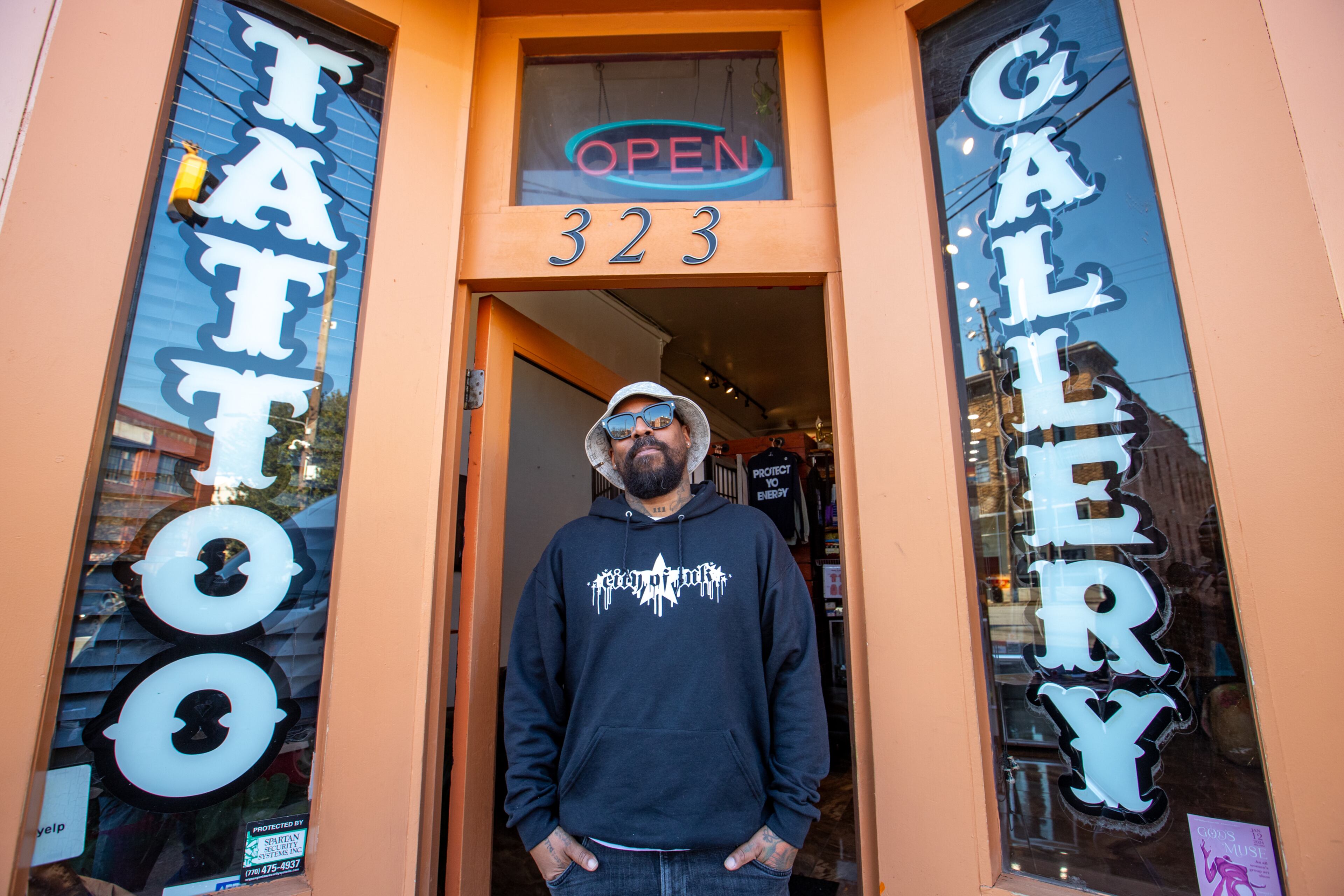 Miya Bailey stands in front of City of Ink on Walker Street in 2024. He received massive public support when he shared that his tattoo shop was at risk of closure due to an ordinance banning new tattoo parlors in Castleberry Hill, an ordinance that was enacted a year after his shop opened. (Jenni Girtman for the AJC)