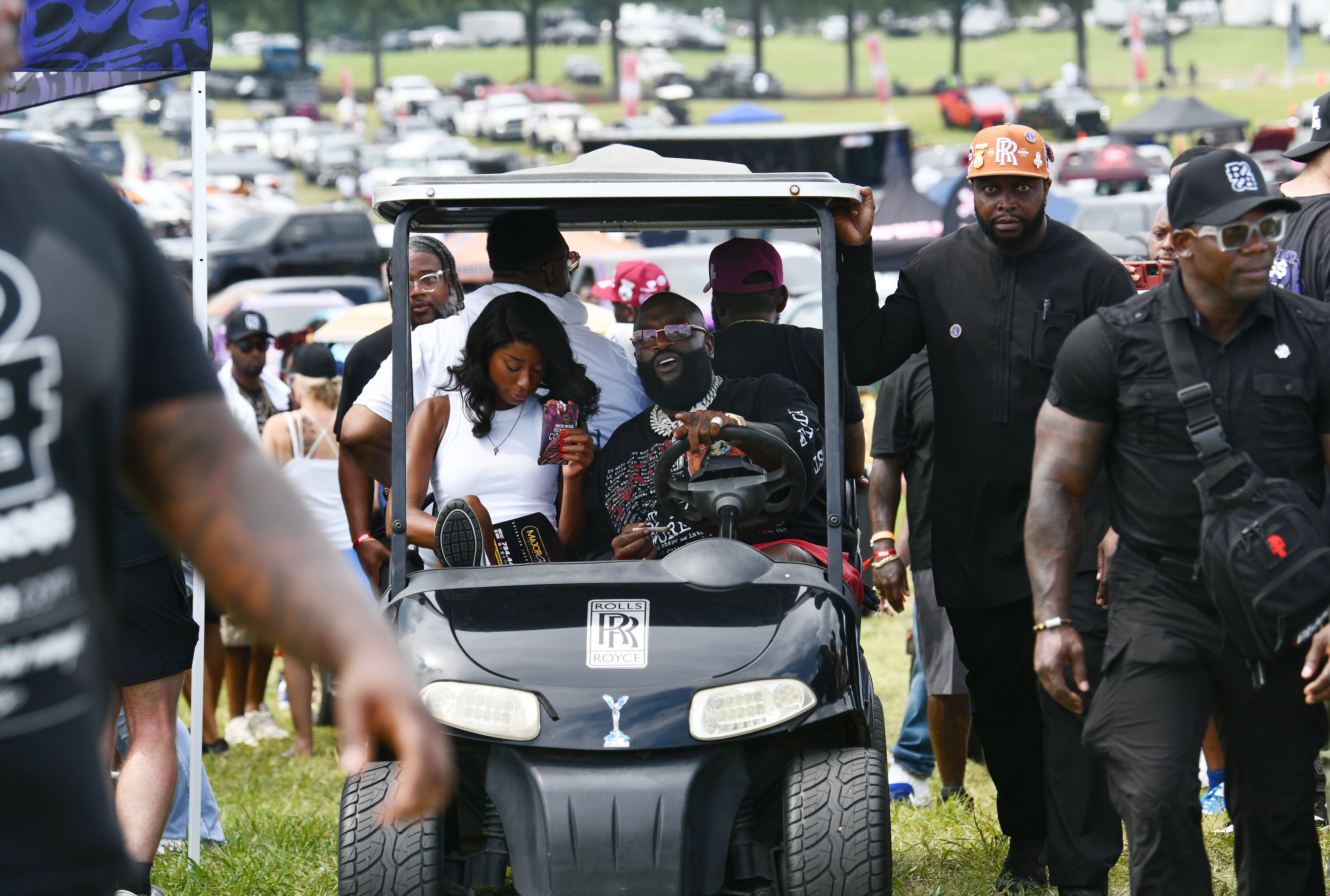 Rick Ross drives his golf cart around the Rick Ross Car Show on Saturday at the Promise Land, his mansion in Fayetteville. The car show included a market with more than 30 vendors, food trucks, fleets of classic/custom automobiles, luxury vehicles, boats, RVs and trailers on the front lawn of the mansion. There were also performances by Plies, Ross' new signee, Nino Breeze, and Ross himself. (Hyosub Shin/AJC)