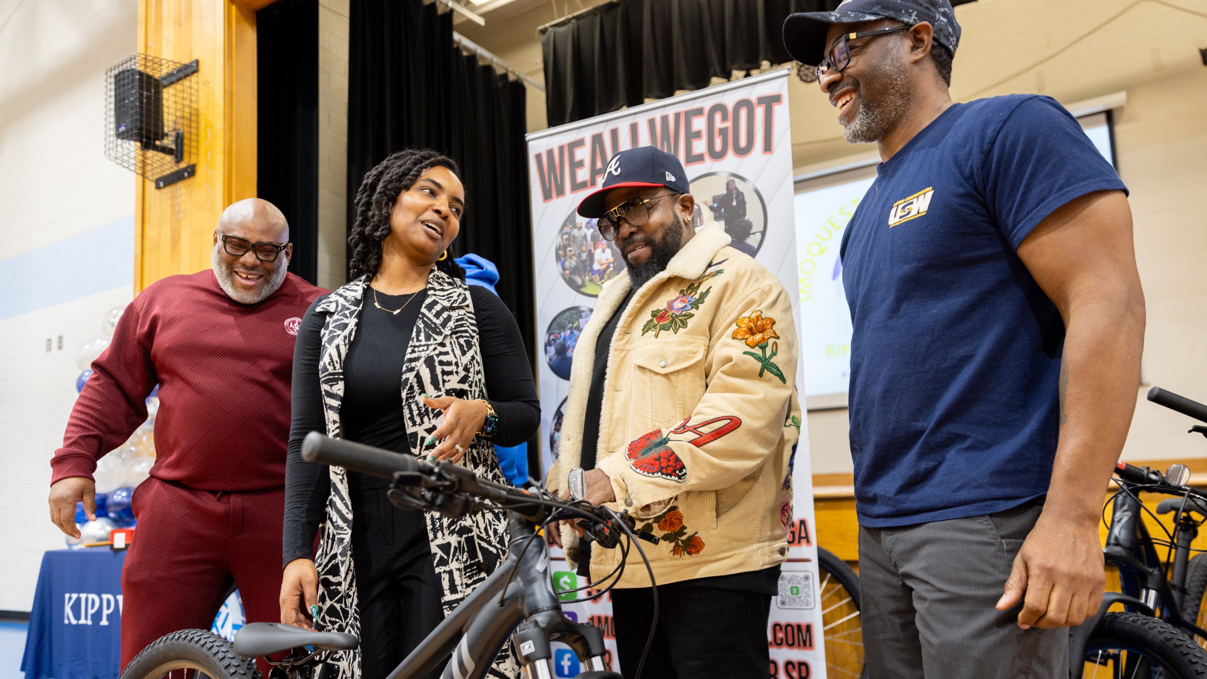 Travis Barber of 1 Mo ?; Jannora Gamble, school social worker; rapper Big Boi; and Lamont Johnson, of 1 Mo ?, laugh during a bike giveaway at Kipp Ways Academy middle school in Atlanta on Monday, December 9, 2024. For the second year in a row Bear Strong partnered with Specialized bikes and Senoia bike shop to award middle school children who have been recognized by their school as most improved, and great attendance. (Arvin Temkar / AJC)